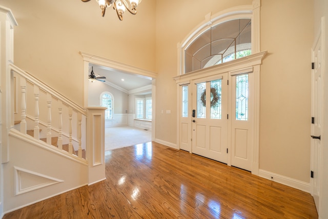 foyer featuring ceiling fan with notable chandelier, ornamental molding, high vaulted ceiling, and hardwood / wood-style flooring