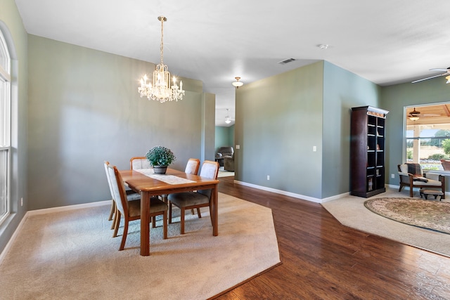 dining space with ceiling fan with notable chandelier and hardwood / wood-style floors