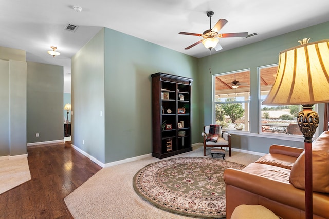 living area featuring ceiling fan and dark wood-type flooring