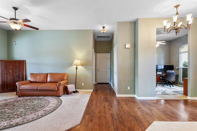 living room featuring ceiling fan with notable chandelier and dark hardwood / wood-style flooring