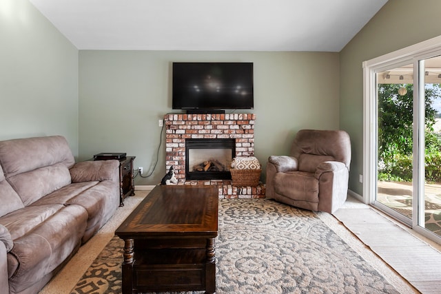 living room with carpet floors, a brick fireplace, vaulted ceiling, and a healthy amount of sunlight