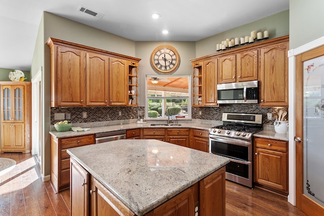 kitchen with dark hardwood / wood-style floors, appliances with stainless steel finishes, a kitchen island, and sink