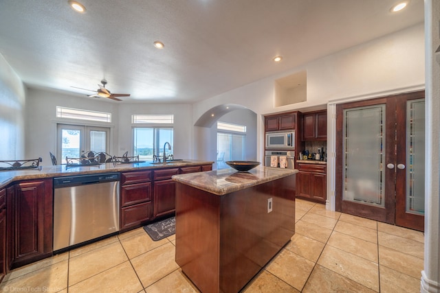 kitchen with sink, stone countertops, a kitchen island, backsplash, and stainless steel appliances