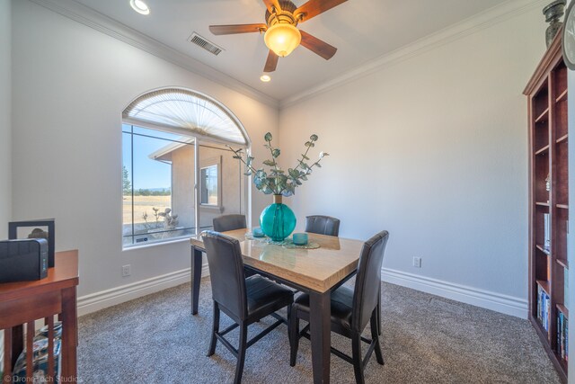 carpeted dining space featuring ornamental molding and ceiling fan