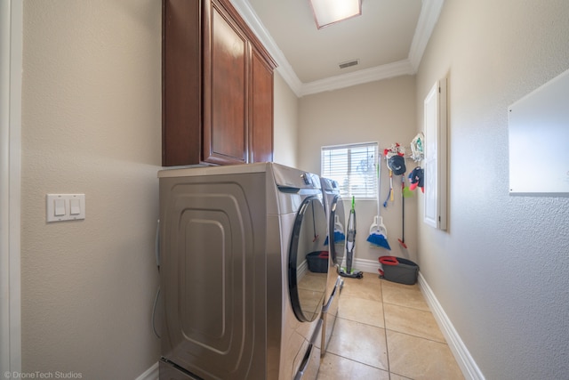 laundry room with crown molding, washing machine and dryer, light tile patterned floors, and cabinets