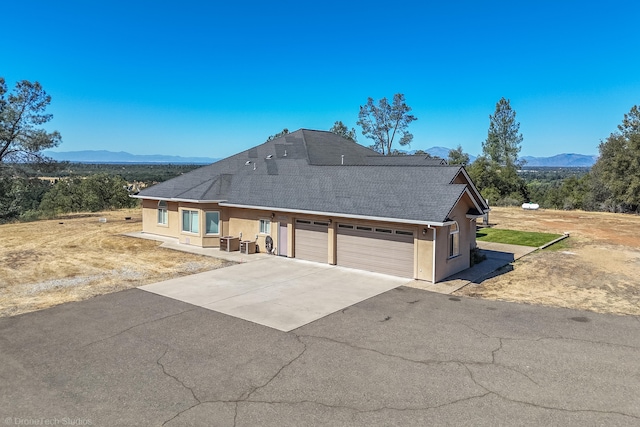 view of front of home featuring central AC unit, a mountain view, and a garage