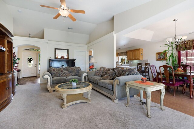 living room featuring ceiling fan with notable chandelier, lofted ceiling, and light wood-type flooring