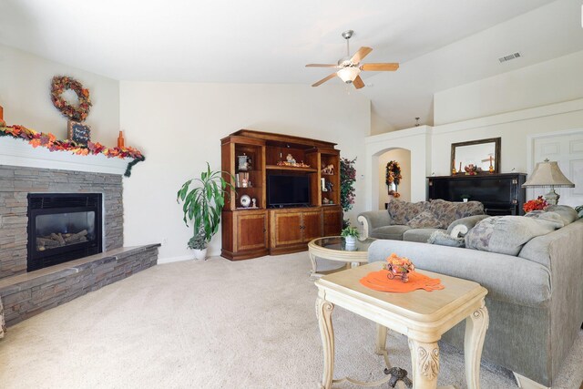 carpeted living room with lofted ceiling, ceiling fan, and a stone fireplace