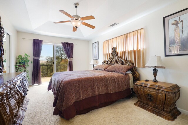 carpeted bedroom featuring access to outside, a tray ceiling, and ceiling fan