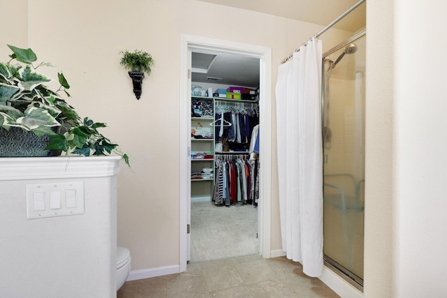 bathroom featuring walk in shower, toilet, and tile patterned flooring