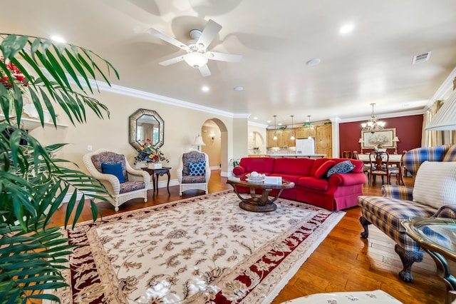 living room featuring ceiling fan with notable chandelier, ornamental molding, and hardwood / wood-style floors