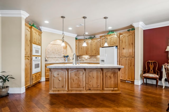 kitchen featuring white appliances, decorative light fixtures, sink, dark hardwood / wood-style floors, and an island with sink