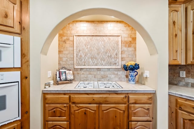 kitchen with tile countertops, backsplash, and white appliances