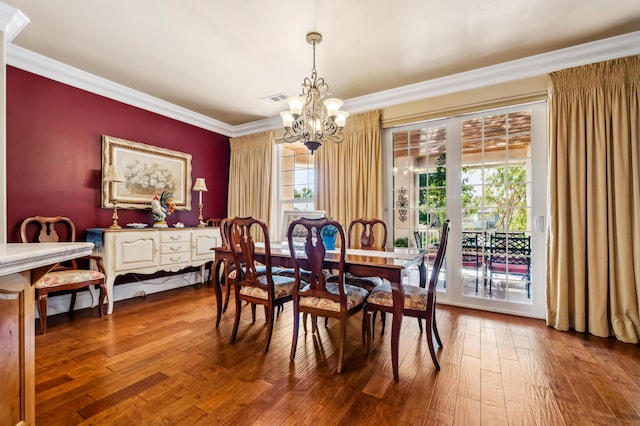 dining room with ornamental molding, hardwood / wood-style floors, and an inviting chandelier