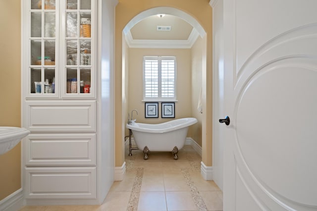 bathroom featuring tile patterned flooring, ornamental molding, and a washtub