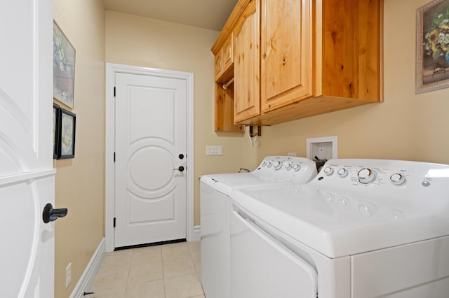 laundry room with washing machine and clothes dryer, cabinets, and light tile patterned floors