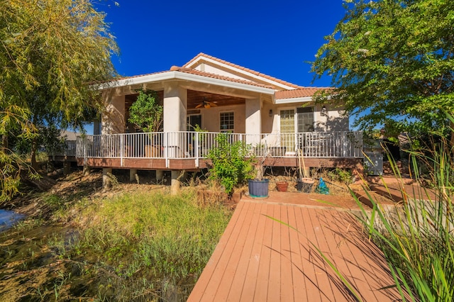 back of house with ceiling fan and a deck