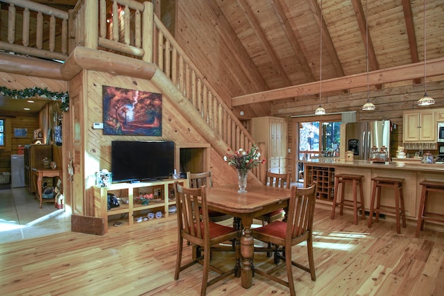 dining space with light wood-type flooring, beamed ceiling, wood walls, high vaulted ceiling, and wooden ceiling