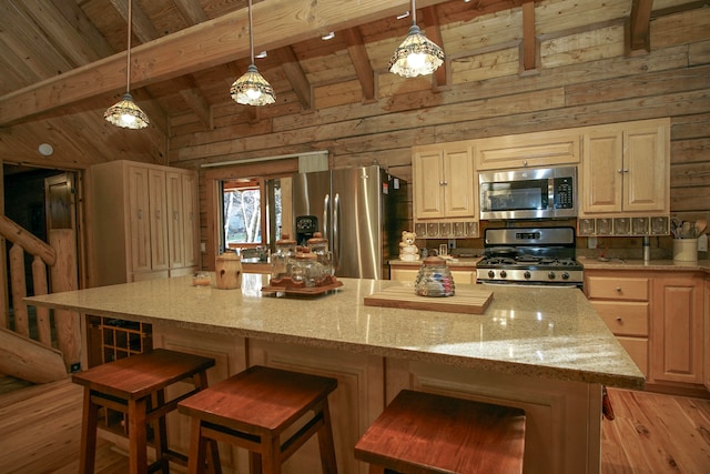 kitchen with wood walls, a kitchen island, appliances with stainless steel finishes, lofted ceiling with beams, and light hardwood / wood-style floors