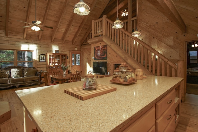 kitchen with ceiling fan, light stone countertops, wood walls, decorative light fixtures, and light wood-type flooring