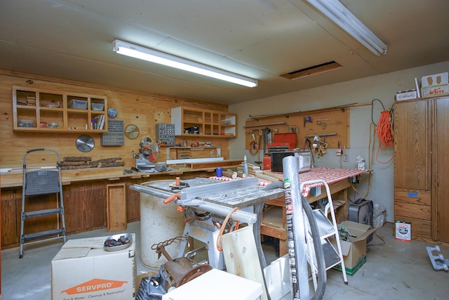 miscellaneous room featuring wood walls and a workshop area