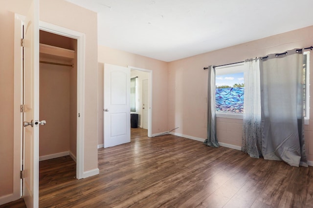 unfurnished bedroom featuring a closet, dark hardwood / wood-style floors, and a walk in closet