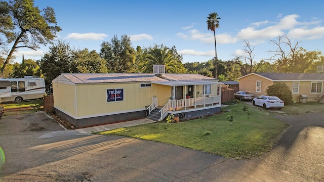 manufactured / mobile home featuring central air condition unit, a front yard, and covered porch