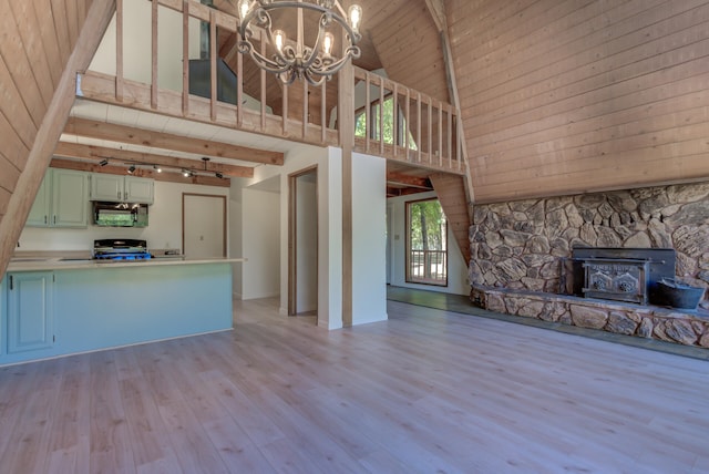 unfurnished living room with a chandelier, rail lighting, light wood-type flooring, high vaulted ceiling, and a fireplace