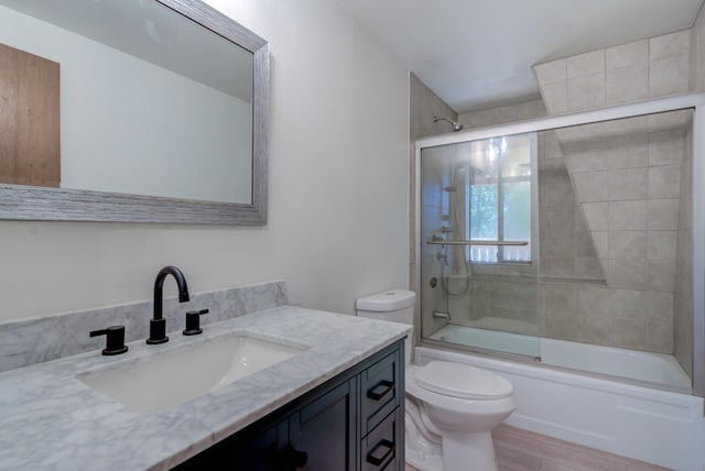 full bathroom with shower / bath combination with glass door, toilet, and vanity