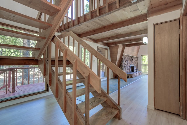 staircase featuring hardwood / wood-style floors, a fireplace, wooden ceiling, and vaulted ceiling with beams