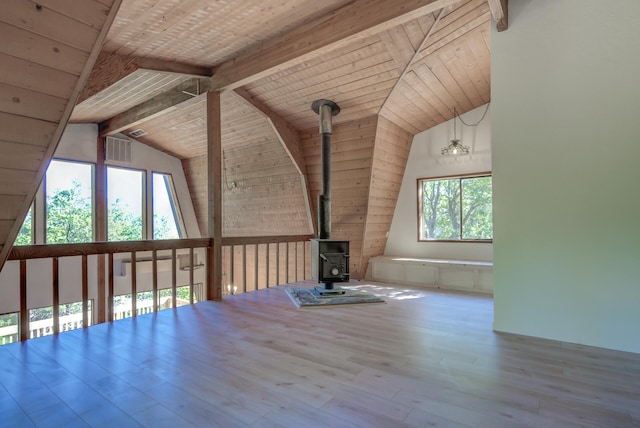 additional living space featuring light wood-type flooring, wooden ceiling, a wood stove, and vaulted ceiling with beams