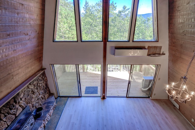 doorway to outside featuring wooden walls, an inviting chandelier, and light hardwood / wood-style flooring