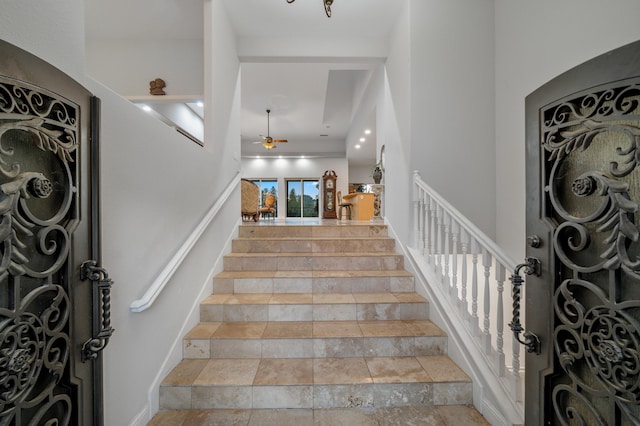 stairway featuring ceiling fan