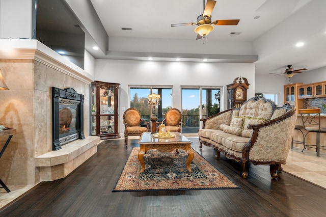 living room with hardwood / wood-style floors, a high ceiling, a fireplace, and ceiling fan