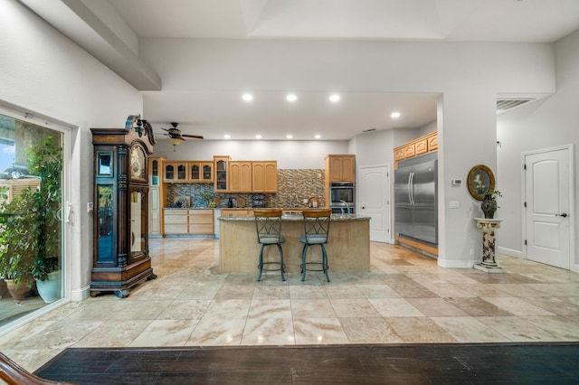 kitchen with tasteful backsplash, appliances with stainless steel finishes, a center island, ceiling fan, and a breakfast bar area