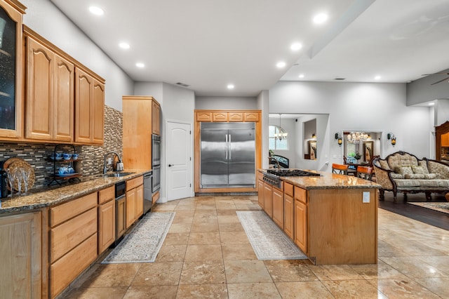 kitchen featuring appliances with stainless steel finishes, sink, hanging light fixtures, decorative backsplash, and an inviting chandelier