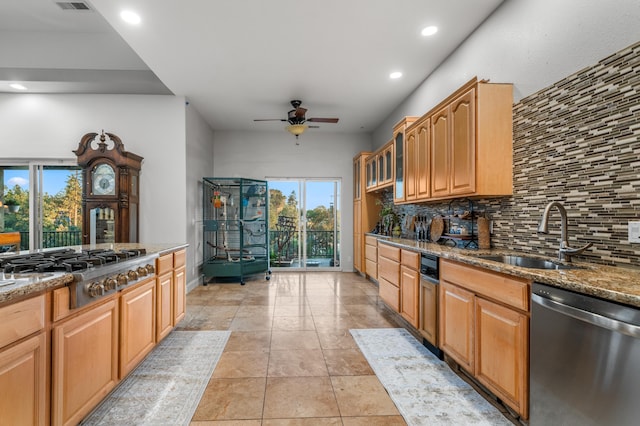 kitchen with decorative backsplash, stainless steel appliances, sink, light stone counters, and ceiling fan