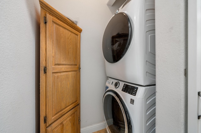 clothes washing area featuring cabinets and stacked washer / dryer