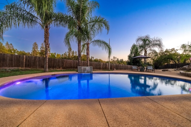 pool at dusk featuring a patio area