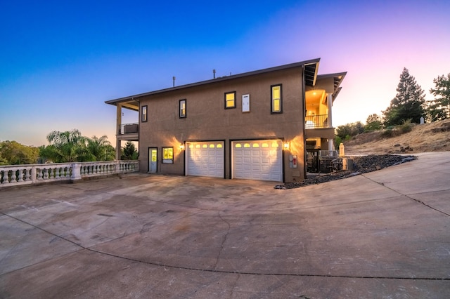 property exterior at dusk with a balcony and a garage