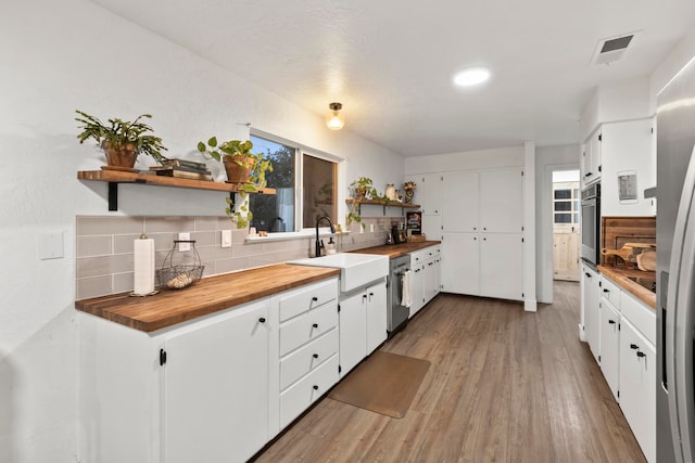 kitchen with white cabinets, butcher block counters, hardwood / wood-style floors, and sink