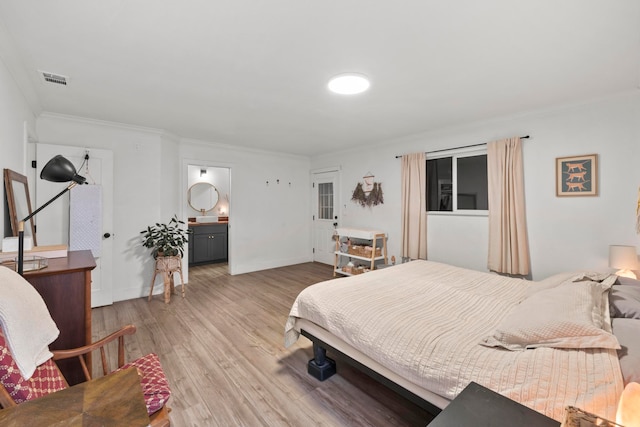 bedroom featuring ornamental molding, ensuite bath, and light hardwood / wood-style floors