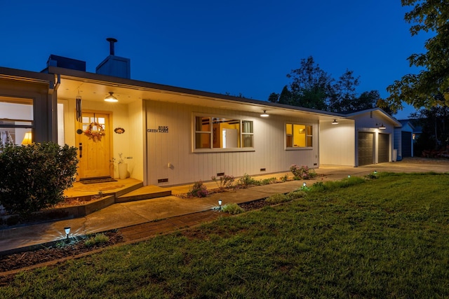 back of house featuring a lawn and a garage