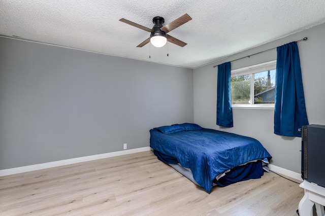 bedroom featuring ceiling fan, light hardwood / wood-style flooring, and a textured ceiling