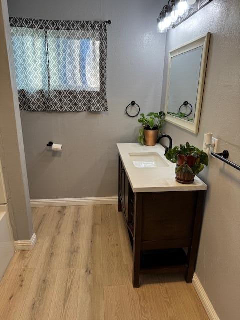 bathroom with a tub to relax in, vanity, and hardwood / wood-style flooring