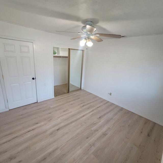 unfurnished bedroom with ceiling fan and light wood-type flooring