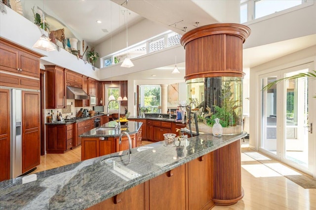 kitchen with light hardwood / wood-style floors, high vaulted ceiling, sink, and pendant lighting