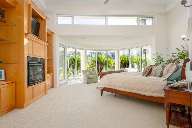 carpeted bedroom with ceiling fan, multiple windows, and a high ceiling