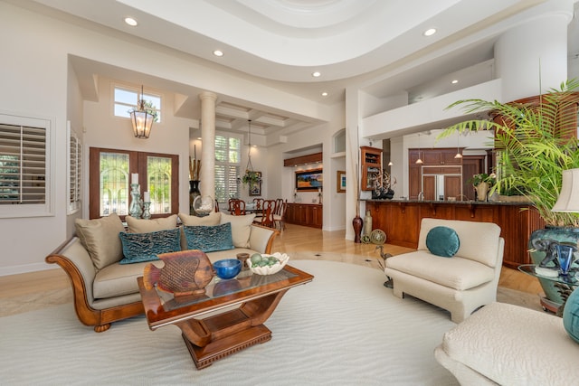 living room with french doors, light hardwood / wood-style floors, a high ceiling, and built in shelves