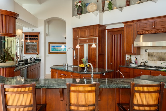 kitchen featuring tasteful backsplash, a breakfast bar area, extractor fan, stainless steel gas cooktop, and a center island